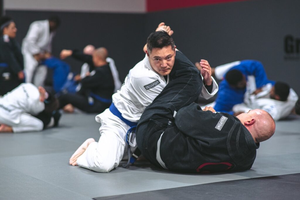 Two men sparring on the floor wearing martial arts uniforms