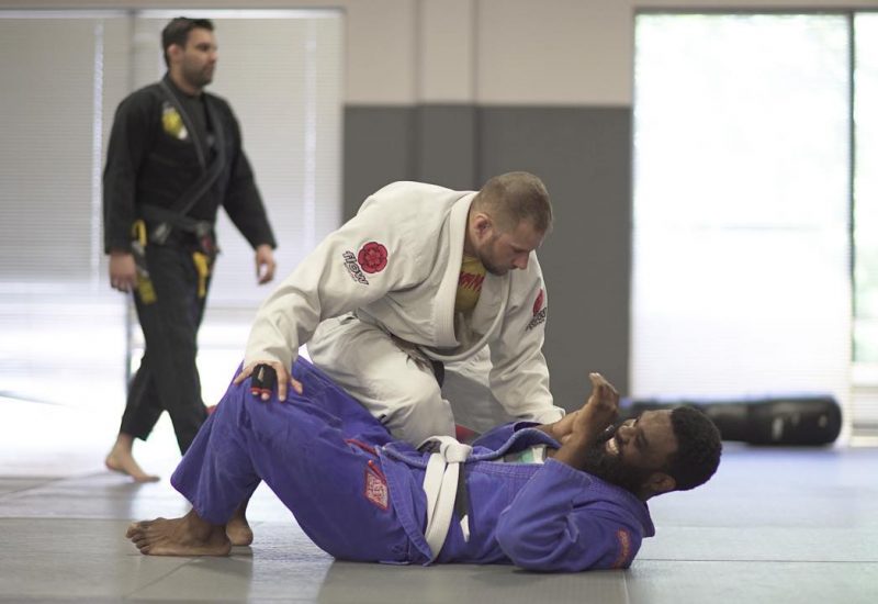 Martial artist smiling on the ground with another man crouched over him