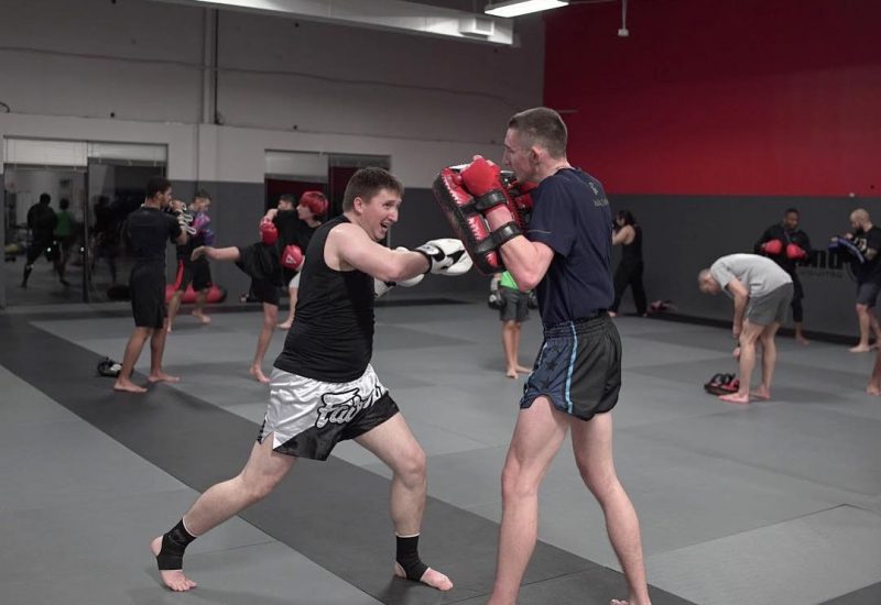 Martial arts student practicing punching on strike pads