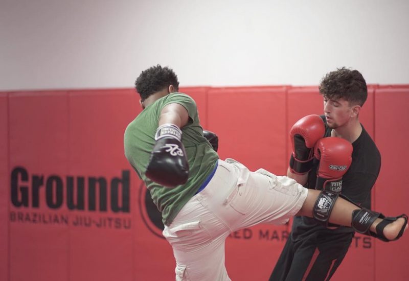 Man kicking another man in the side with boxing gloves on