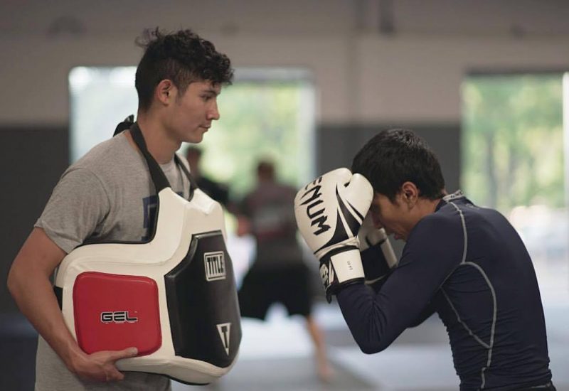 Man practicing punching with trainer