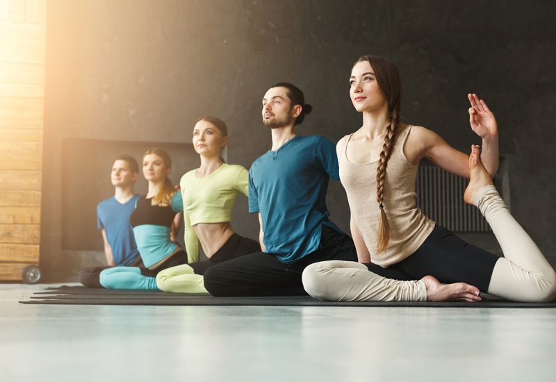 Women and men in yoga class, mermaid pose stretching. Healthy lifestyle in fitness club, copy space